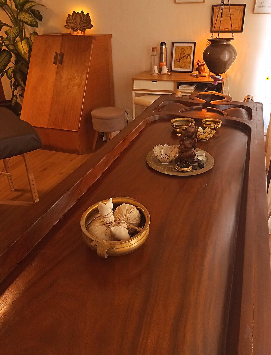 Sala de tratamientos de Tapovan Ayurveda con camilla de madera y cuencos de latón